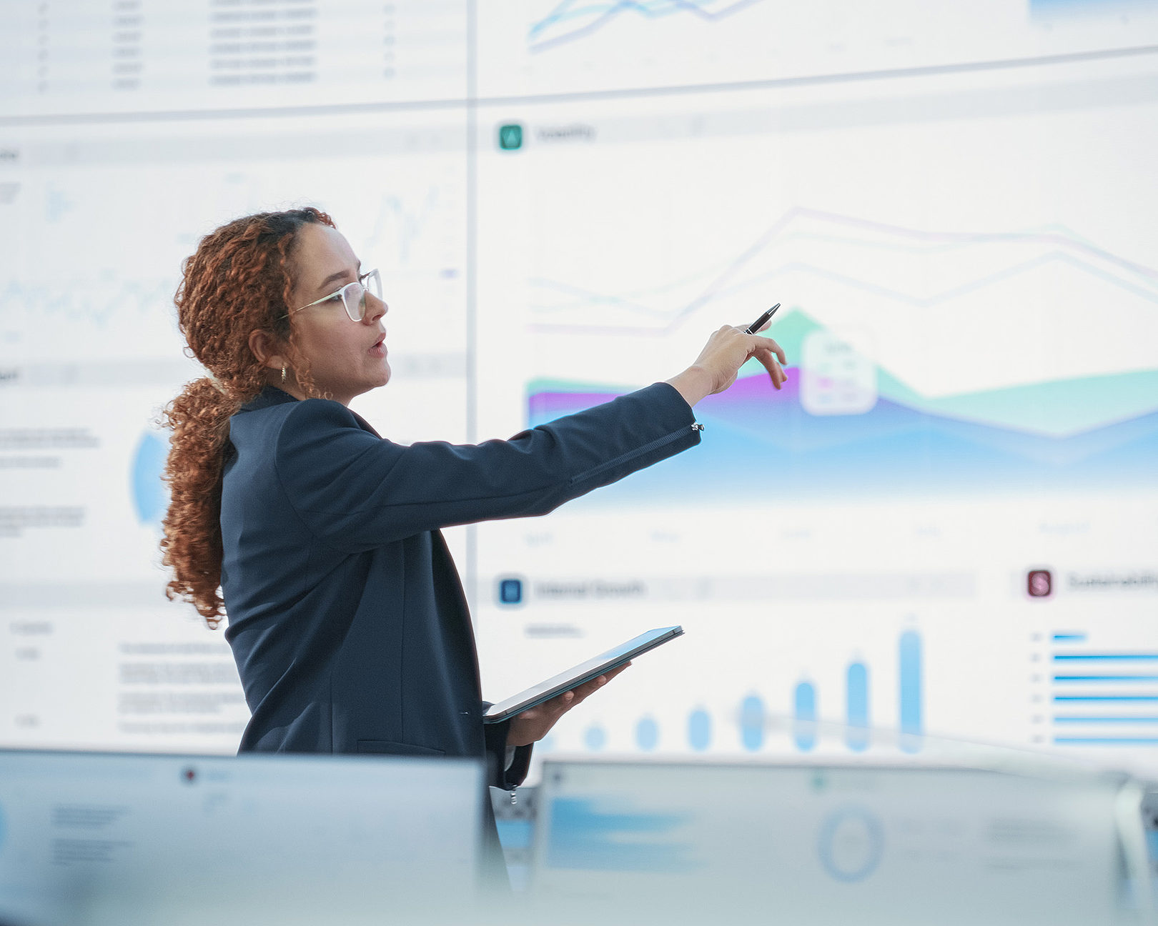 A woman is pointing at a graph on a large screen behind her